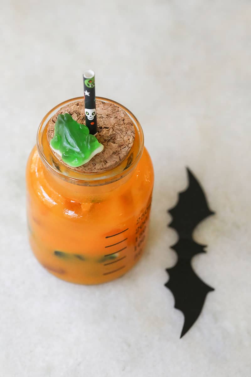 Kids Halloween punch on a marble table with a cork lid and a black Halloween straw.