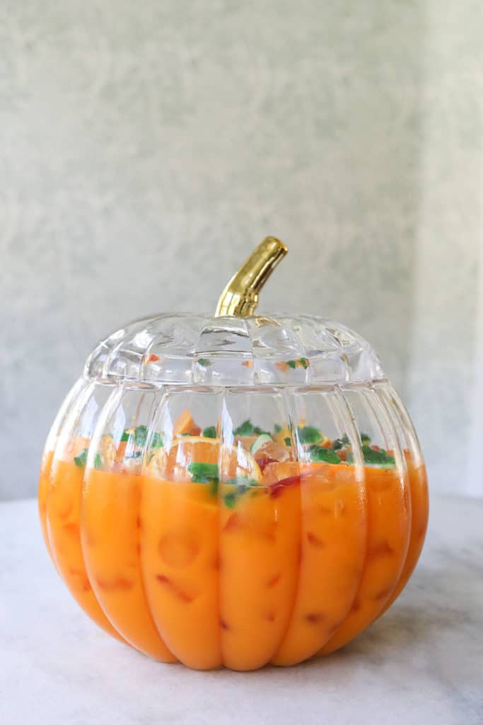 Kids Halloween punch served in a pumpkin punch bowl with gummy worms.