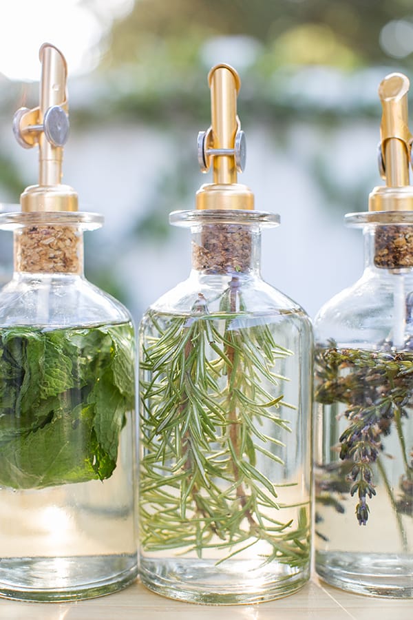 Three bottles of infused simple syrup with rosemary, mint and lavender. 