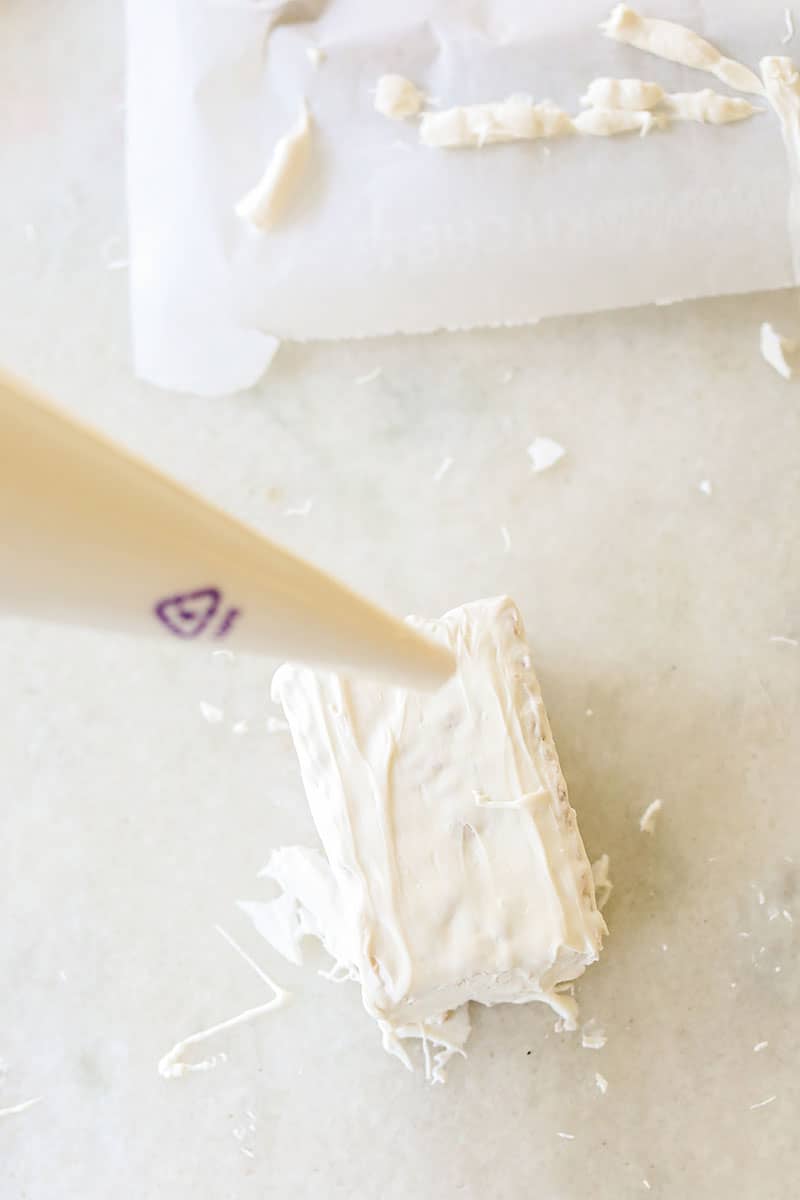 Piping bag making bandages on a dipped white chocolate rice Krispie treat to make mummies. 