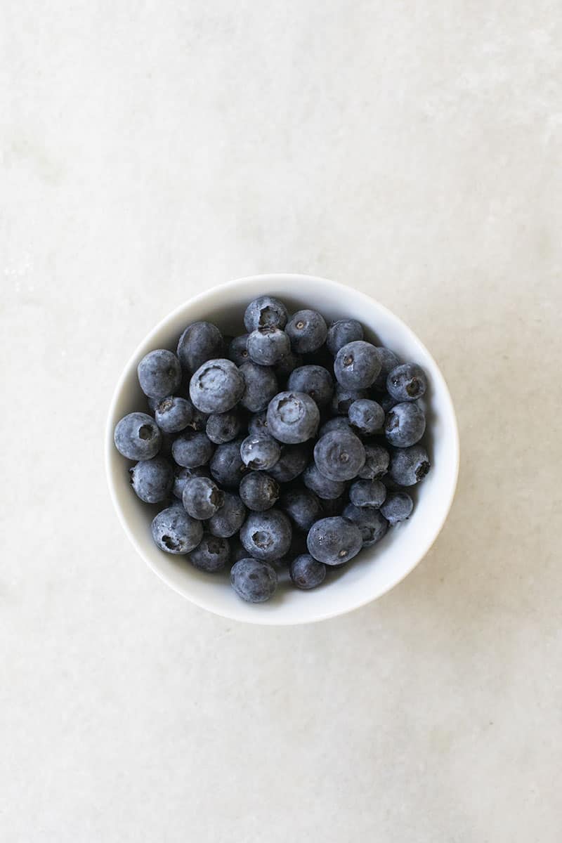 Fresh blueberries in a white bowl on a marble table. 