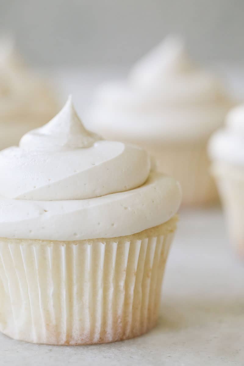 A fluffy white vanilla cupcake with a whit paper and creamy buttercream.