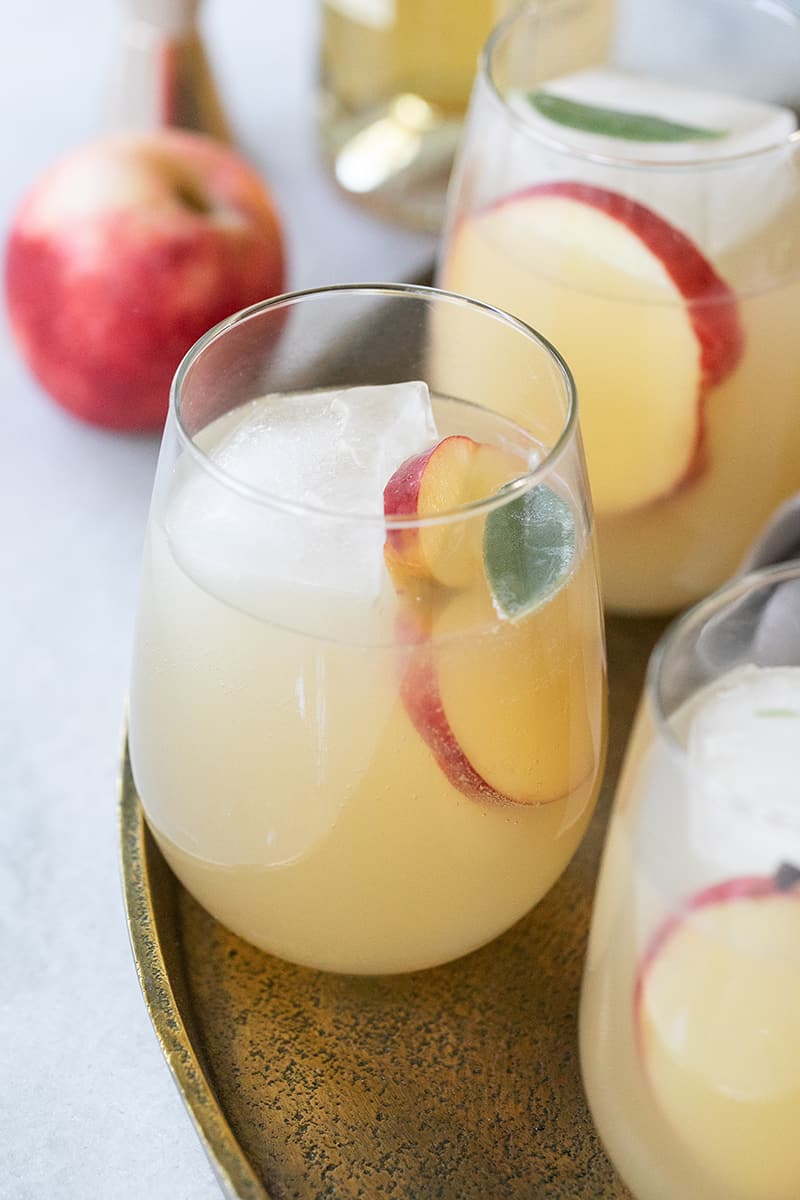 Fall wine spritzer with apple and ginger and Lillet. Served in a glass with fresh apple garnish. 