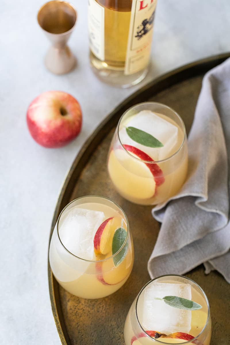 Apple cocktail spritzer for Thanksgiving cocktail on a gold tray with apples and Lillet 