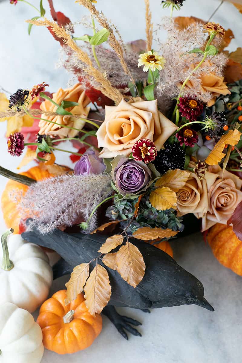 Halloween flowers and pumpkin and crow on a  marble table.