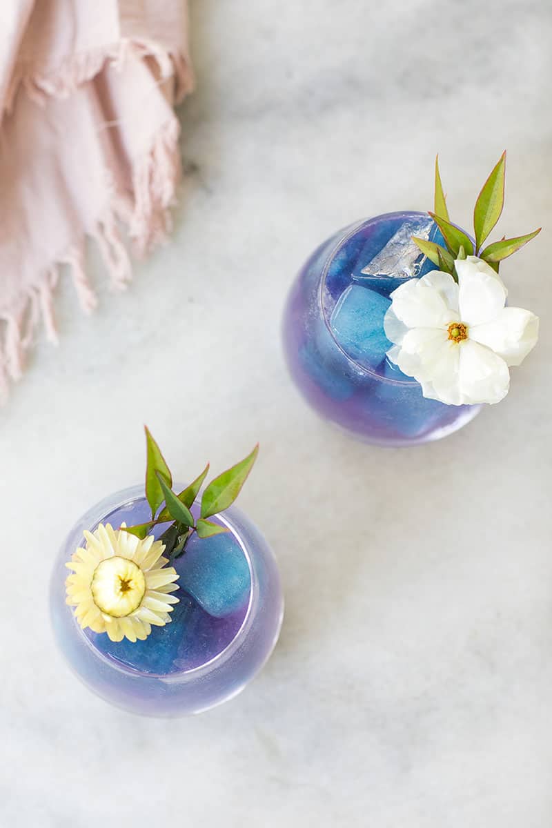 Two purple and blue cocktail Palomas with blue ice cubes and topped with spiked seltzer.