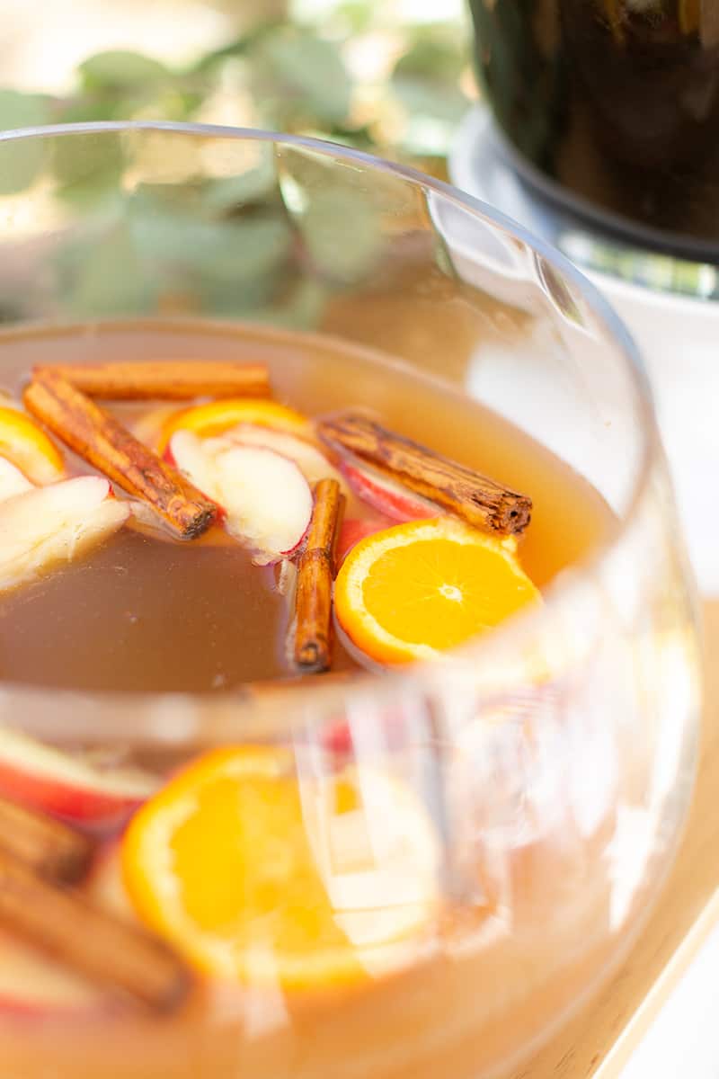 Cocktail punch with apples and cinnamon in a punch bowl.