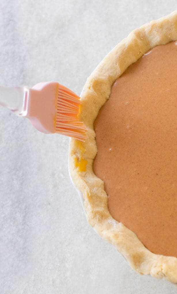 Brushing pumpkin pie crust with butter.