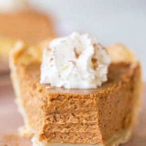 Slice of pumpkin pie with whipped cream on the top.