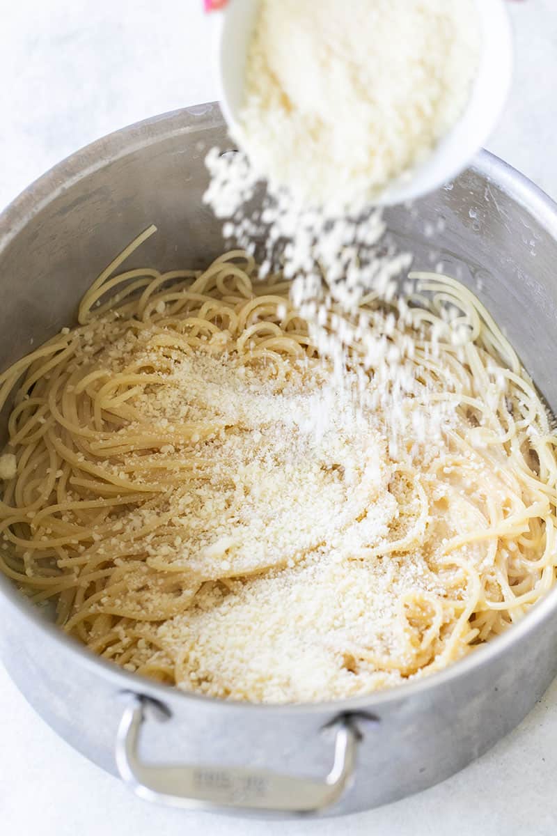 Parmesan cheese pouring into hot noodles. 
