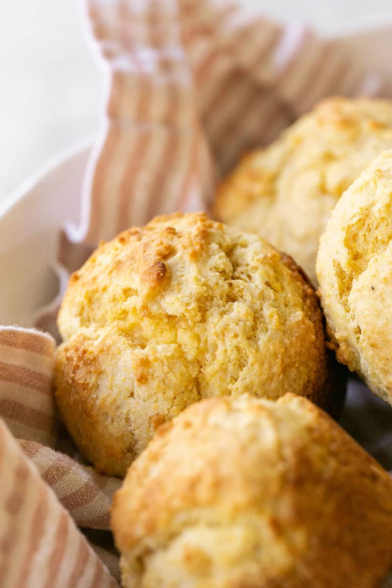 Easy cornbread muffin recipe and cornbread muffins in a bowl with a pink stripe towel.