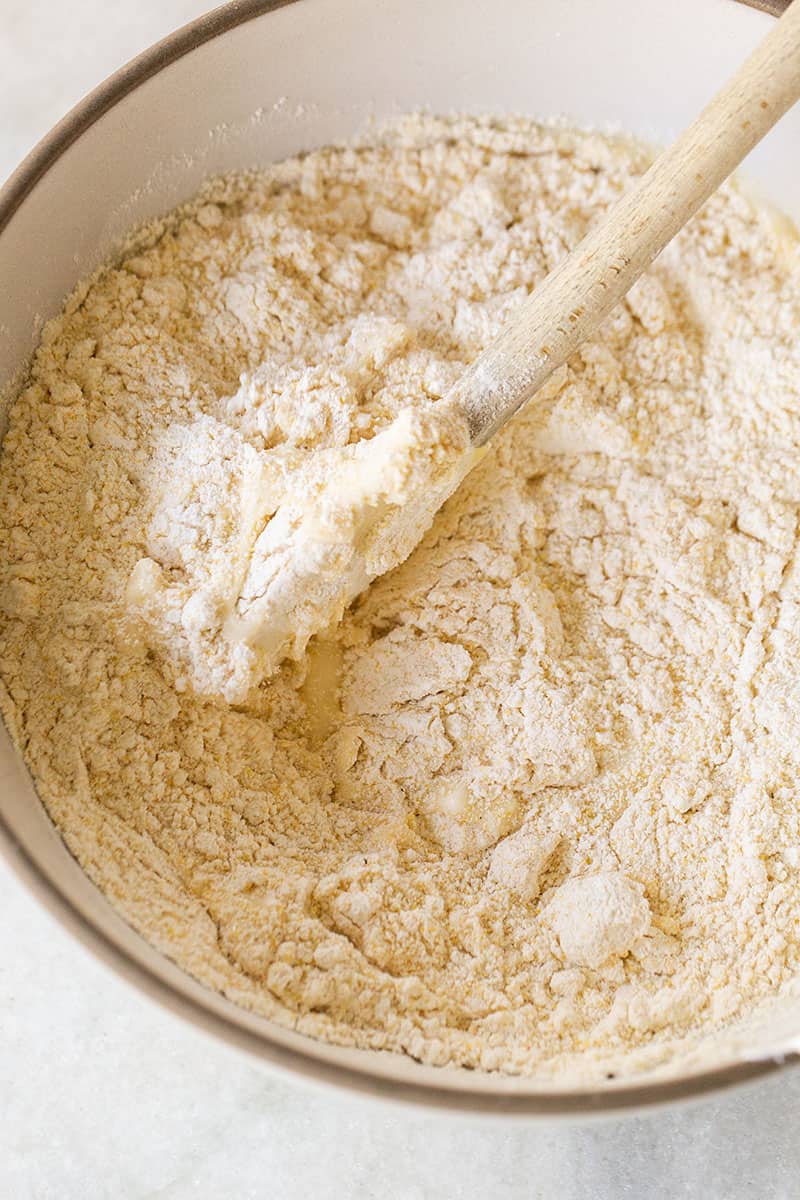 Mixing flour and cornmeal to make homemade cornbread muffins.