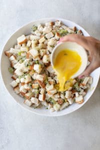 Pouring eggs over stuffing.
