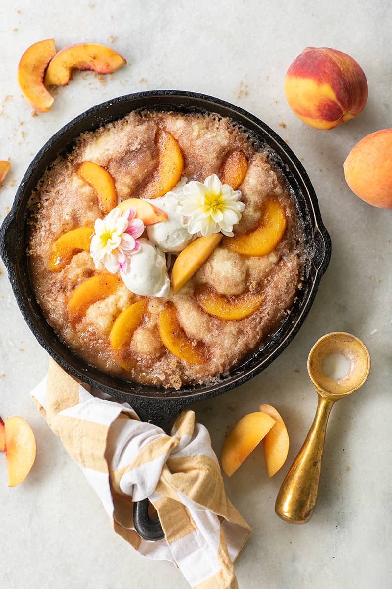 Cast iron skillet peach cake with vanilla ice cream and peaches baked in the batter.