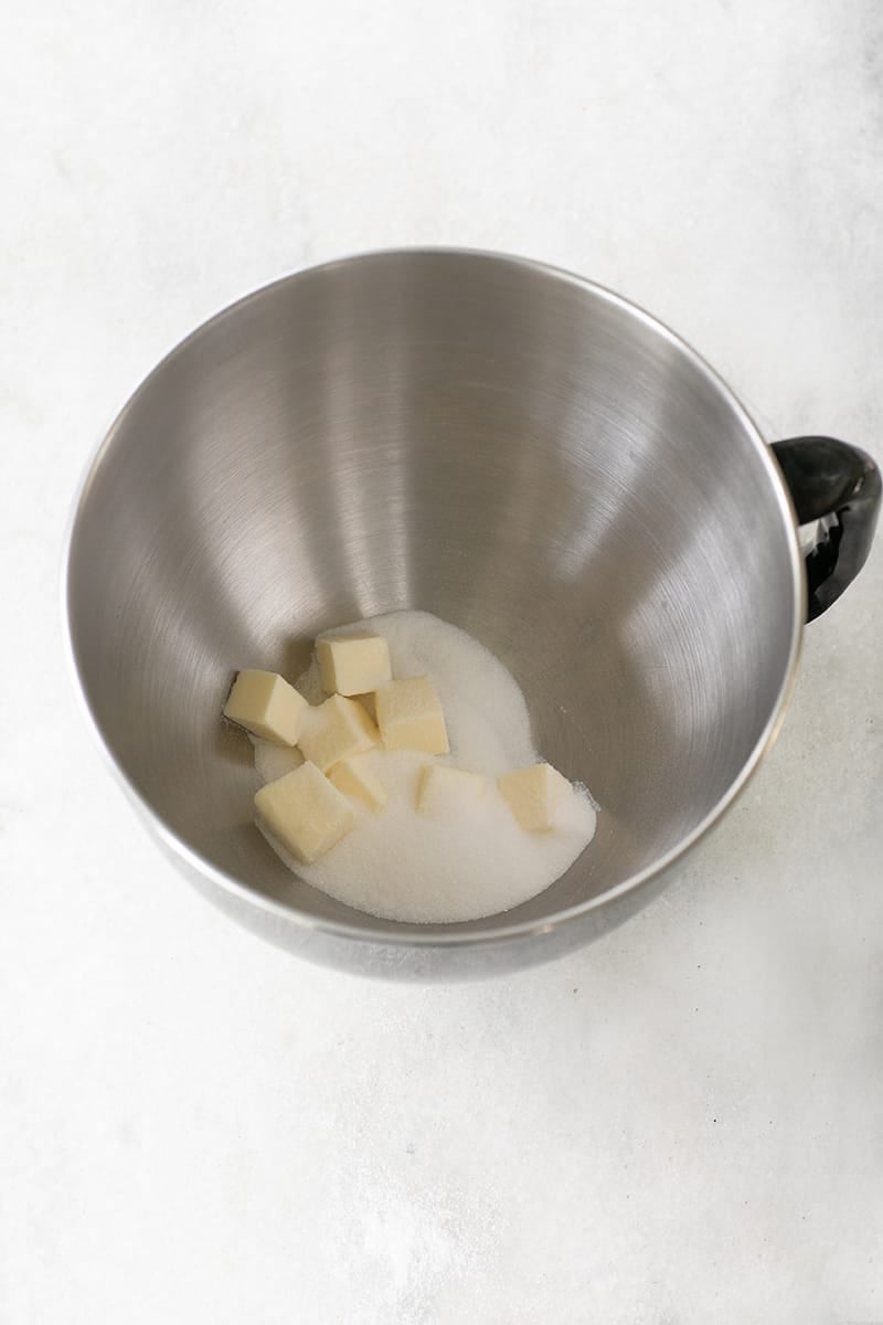Cubed butter and sugar in a mixing bowl.
