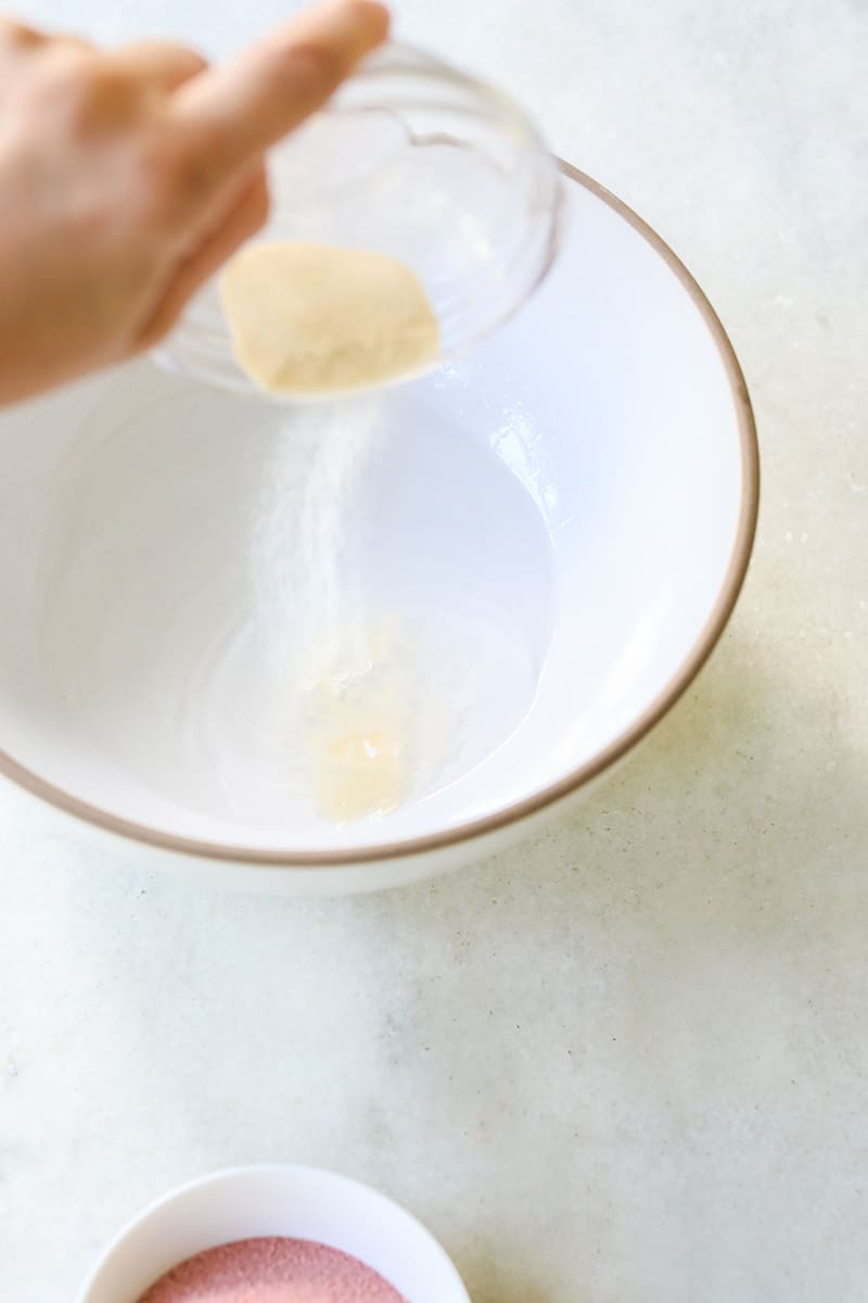 Pouring gelatin into a white bowl to make jello shots.