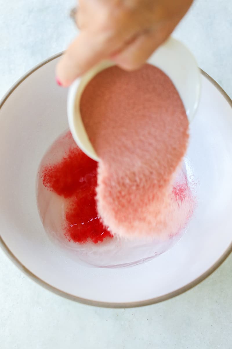Pouring red jello in a bowl with vodka.