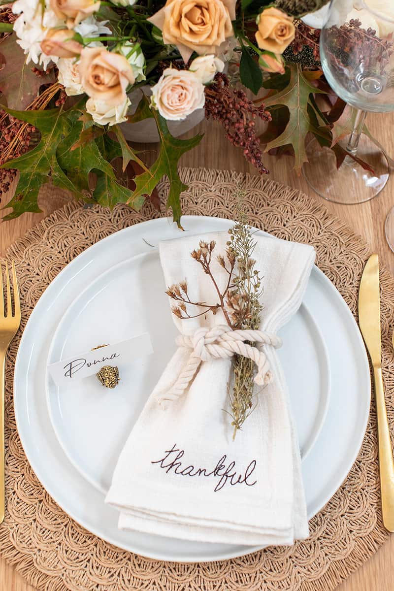 Thanksgiving table setting with thankful napkins, gold silverware and rope.