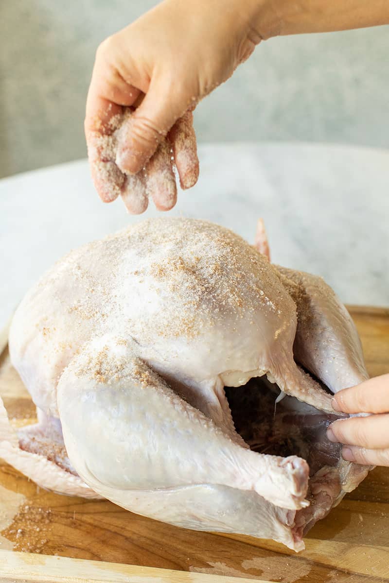 How to dry brine a turkey. Hand rubbing salt and brown sugar all over an uncooked turkey.