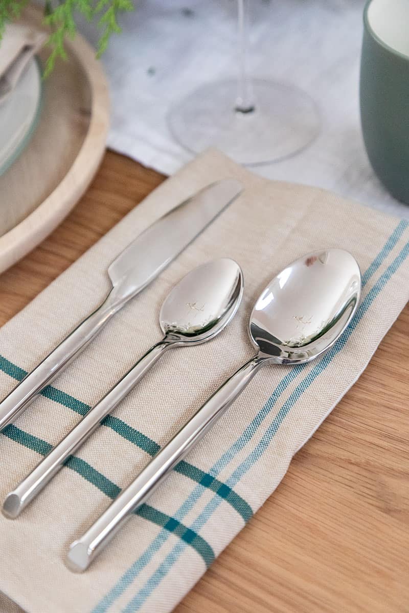 Flatware from Fortessa on a teal and green napkin for Christmas.