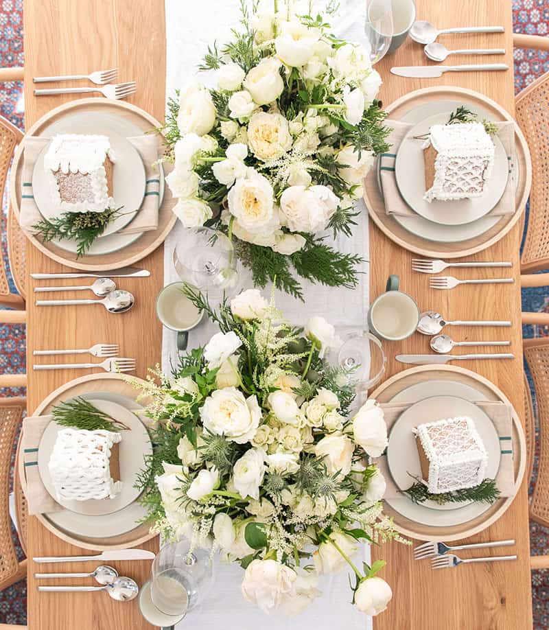 Christmas Eve Dinner Table Setting with flowers, plates, table runner. 