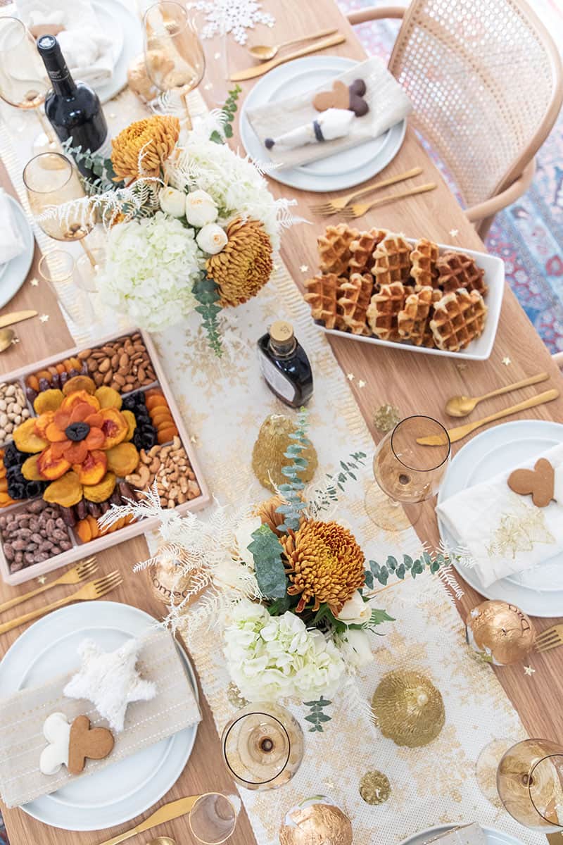 Christmas brunch table setting with flowers, waffles, wine, fruit.