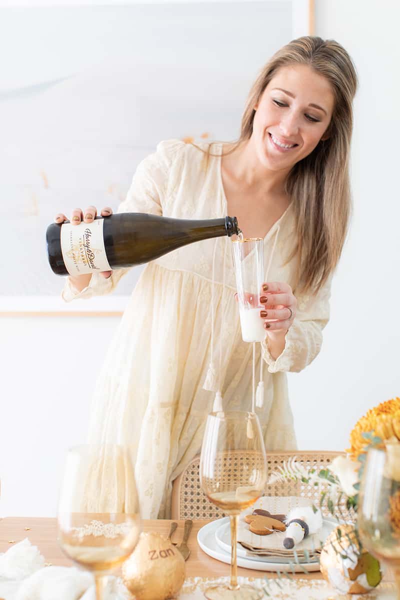 Eden Passante pouring a glass of sparkling white wine.