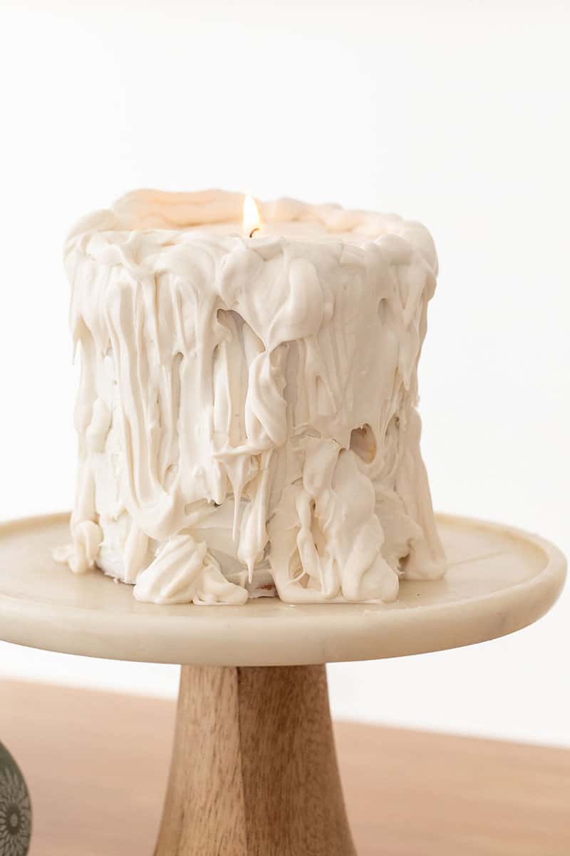 White candle drip cake on marble cake stand.