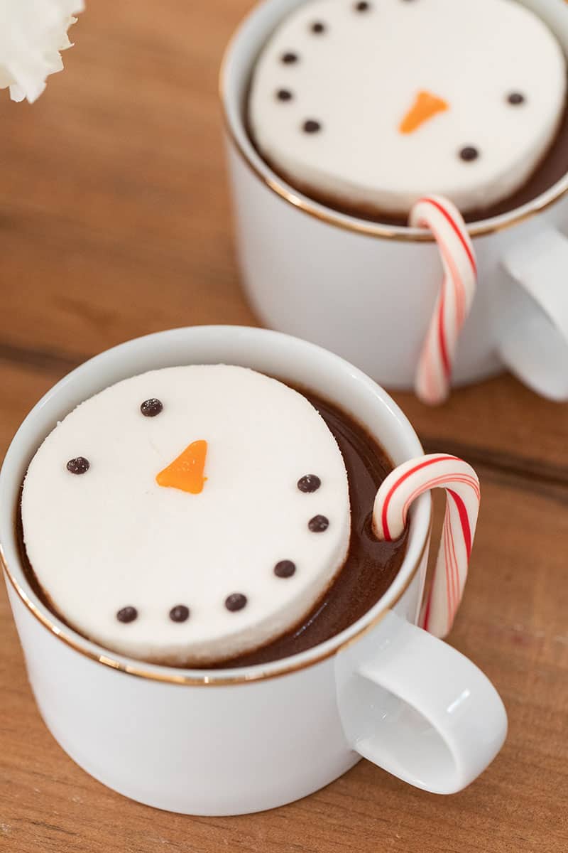 Hot chocolate in white and gold mugs with marshmallow snowmen.
