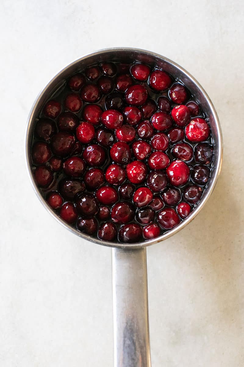 A small saucepan with fresh cranberries, water and sugar.