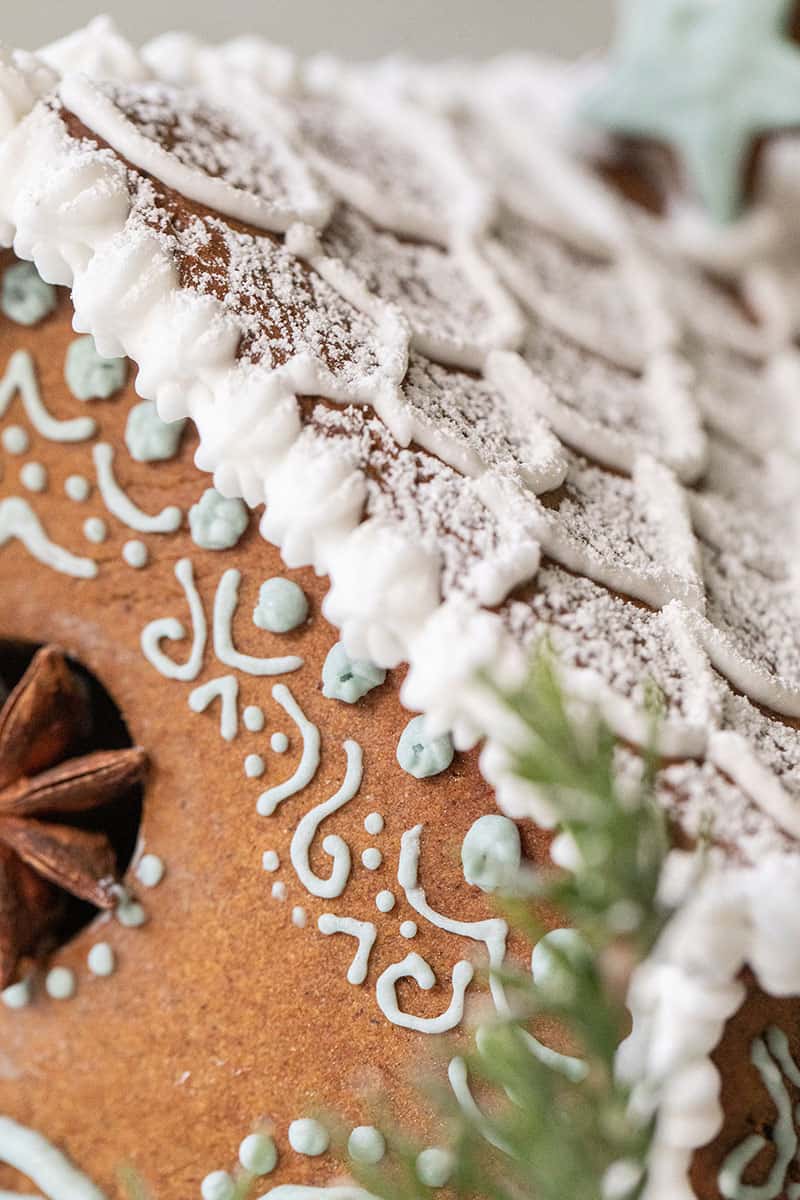 Gingerbread house with royal icing, powdered sugar and decorations.