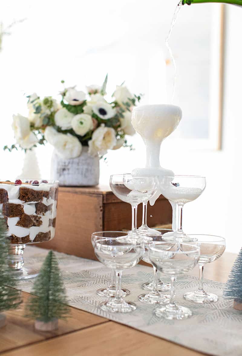 Champagne coupe glasses stacked with Champagne being poured over the top.