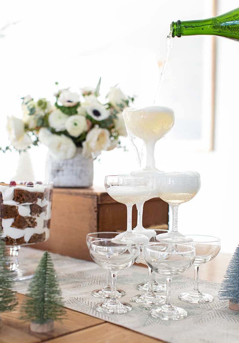 Bottle of Champagne being poured over the coupe glasses.