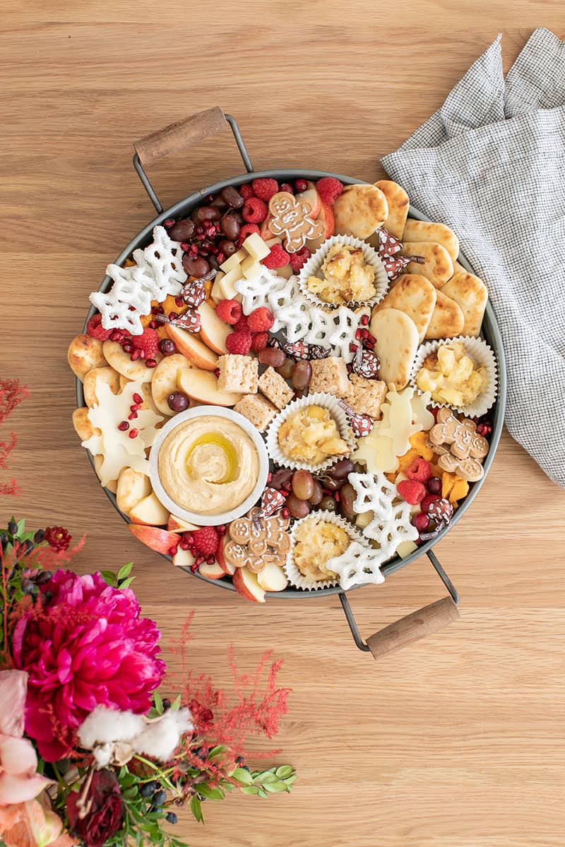 A round tray filled with mini desserts, fruit, hummus and more for a Christmas appetizer platter for kids.