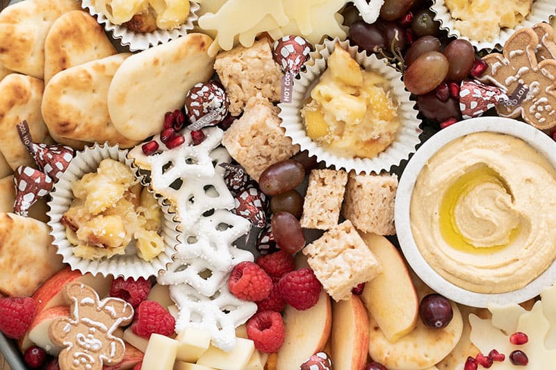 Pita bread, hummus, yogurt covered pretzels, berries, grapes all on a kids appetizer platter.