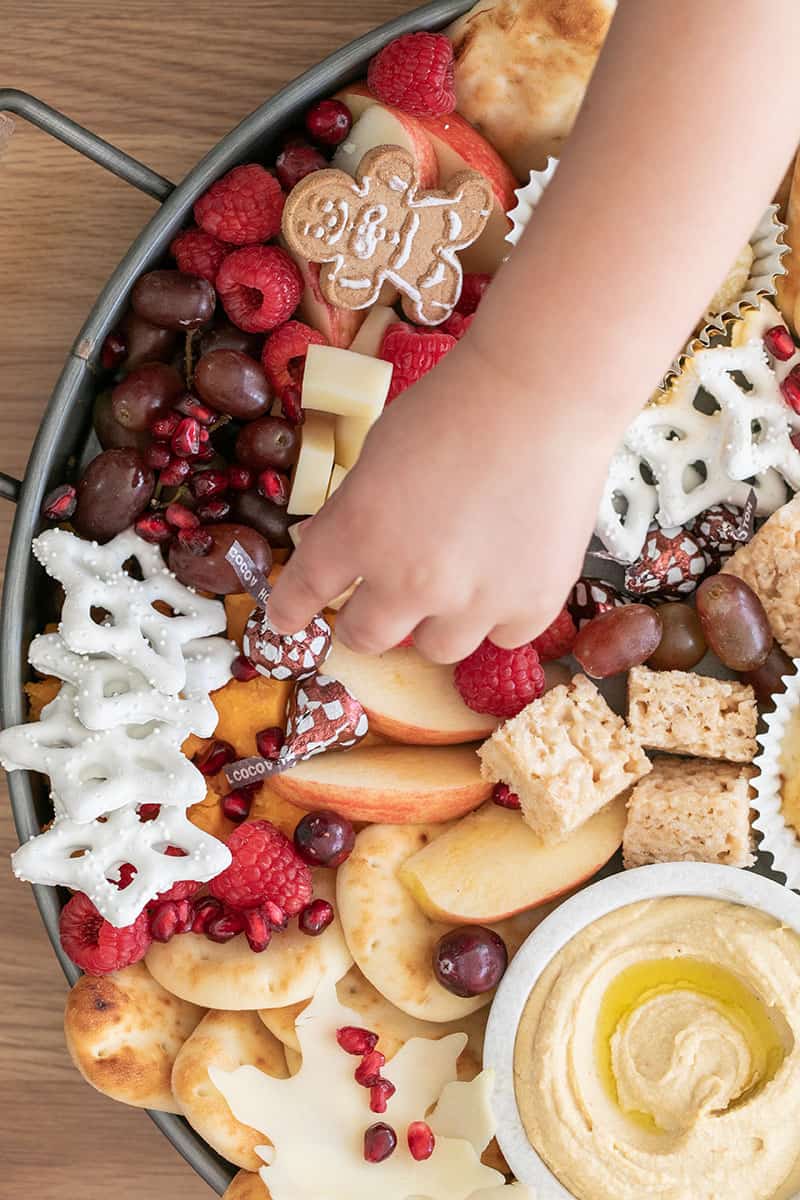 A little hand grabbing a Hersey Kiss on a kids appetizer platter.