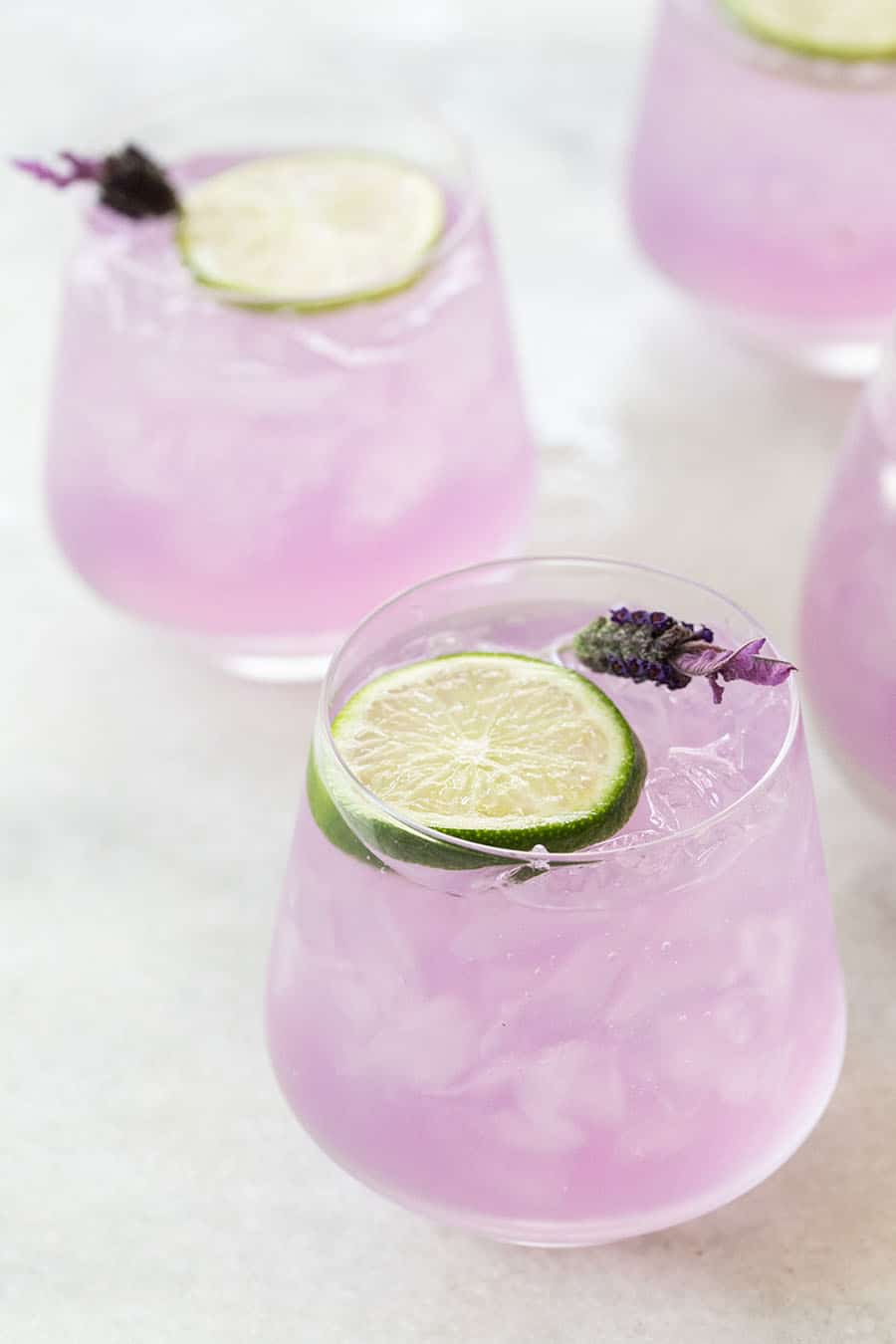 Purple, lavender gin and tonic with a lime slice and fresh lavender. 