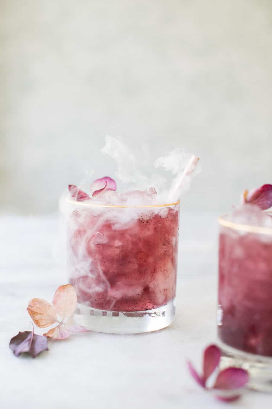 A smoking açaí gin and tonic with edible flowers.