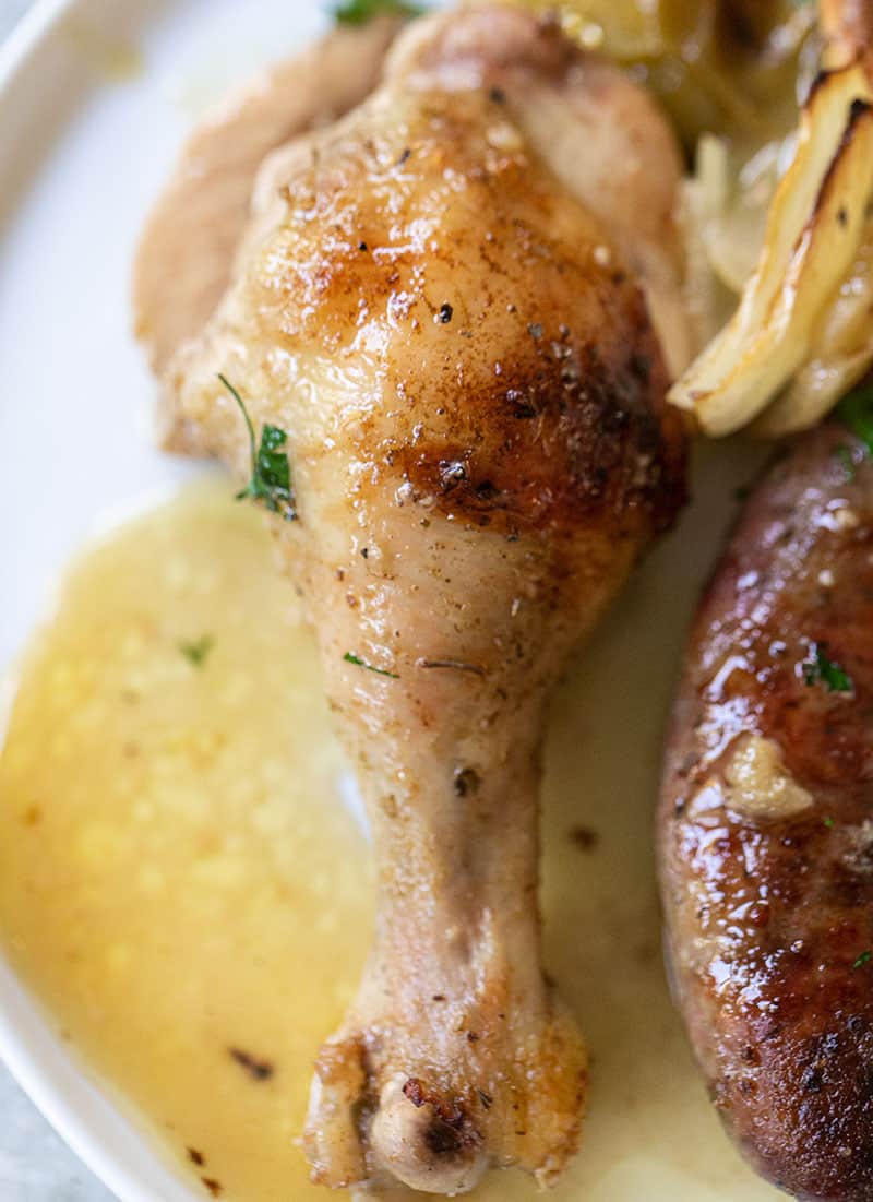 Close up photo of a baked golden brown chicken leg with juice.