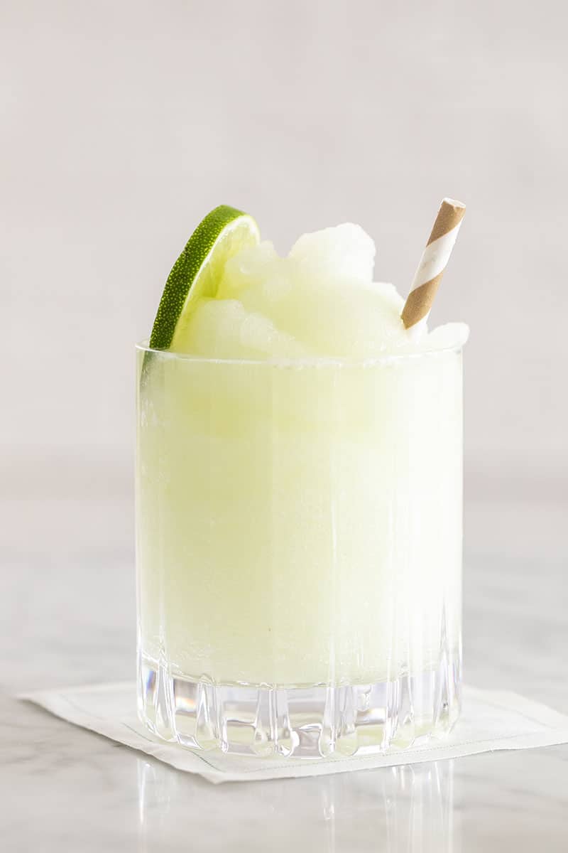 Frozen gin and tonic with straw and lime slice