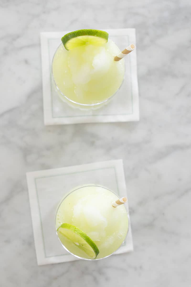 Frozen gin and tonic cocktail with straw and lime wedge.