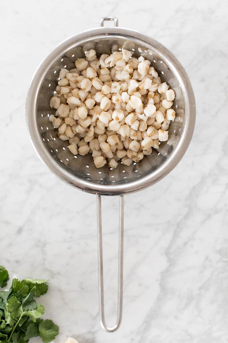 Hominy in a strainer for pozole soup - pozole rojo recipe, ancho chiles