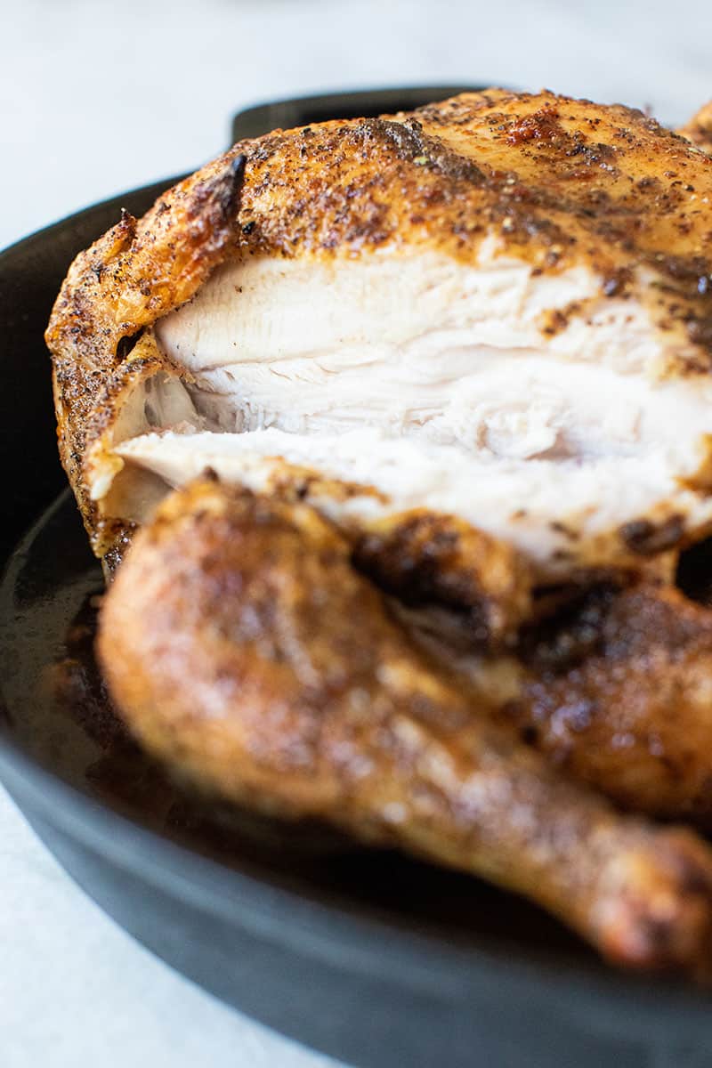 Whole roasted chicken in cast iron pan - chicken breast, roast chicken rest, cavity of the chicken, chicken legs, crispy skin