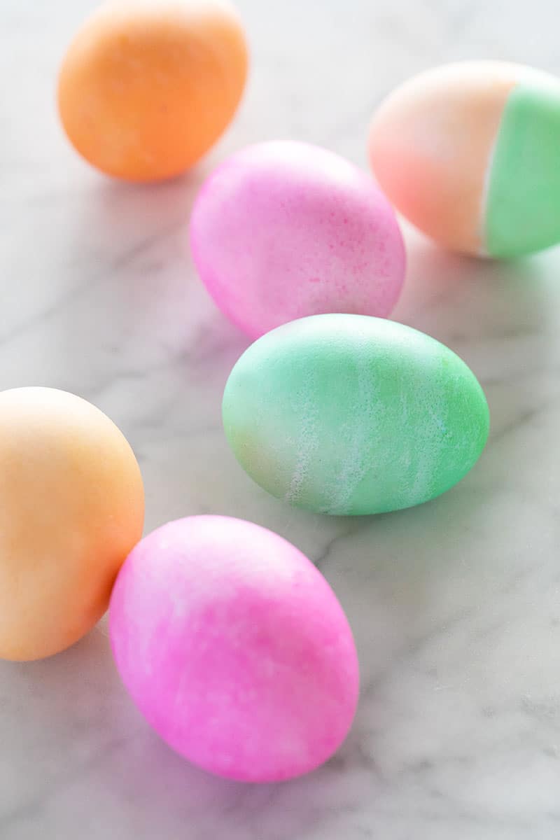 Pink, orange and green Easter eggs in a table.