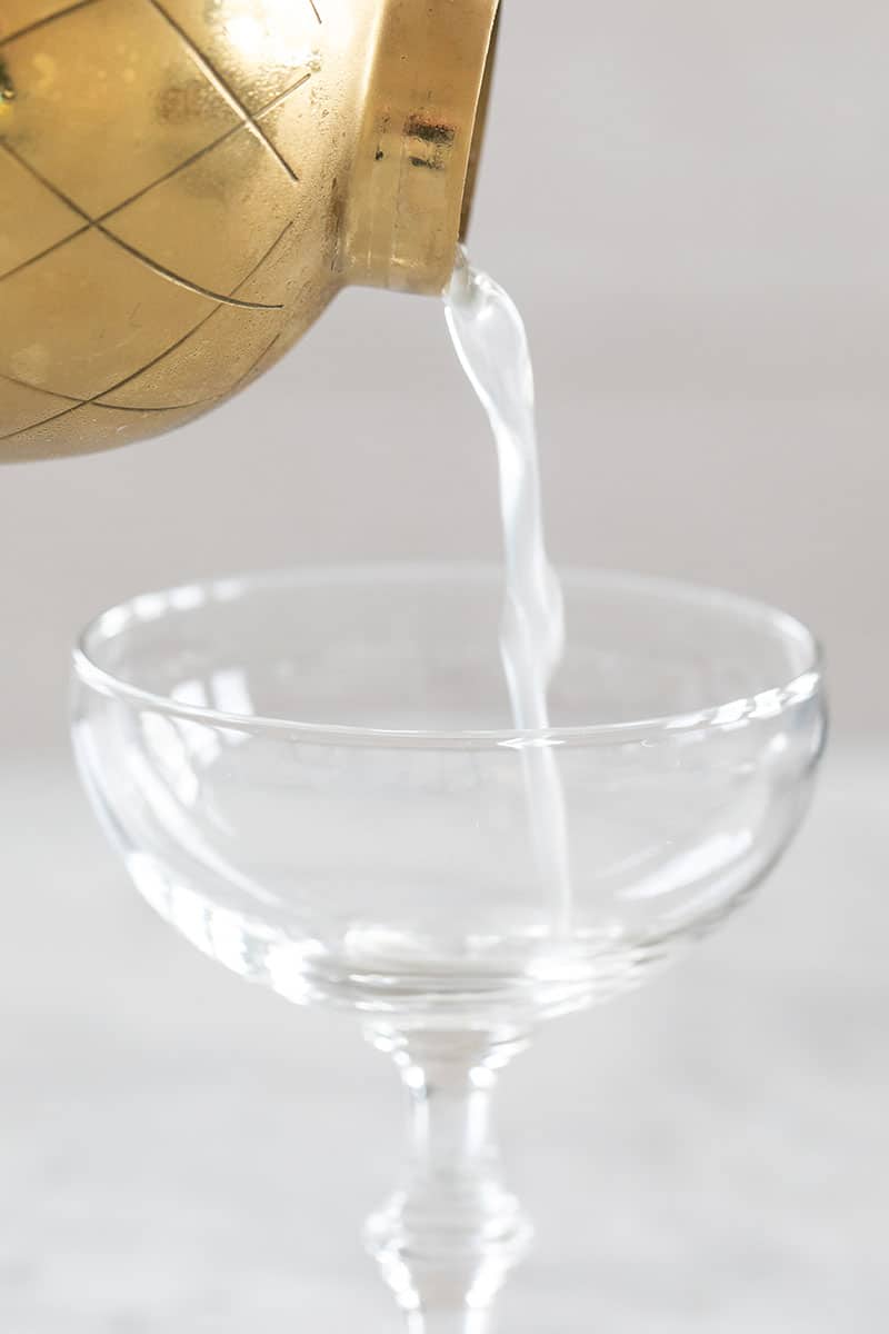 Pouring a cocktail in a coupe glass.