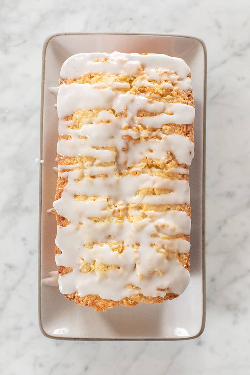 Loaf cake with coconut glaze poured over the top.