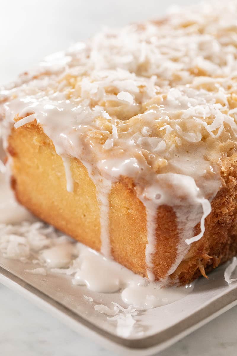 Homemade coconut loaf cake with a coconut glaze and topped with shredded coconut.