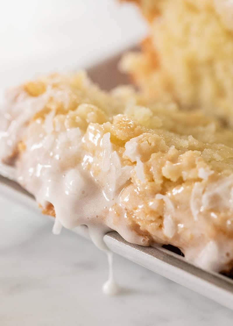 Coconut glaze dripping off a slice of coconut bread.