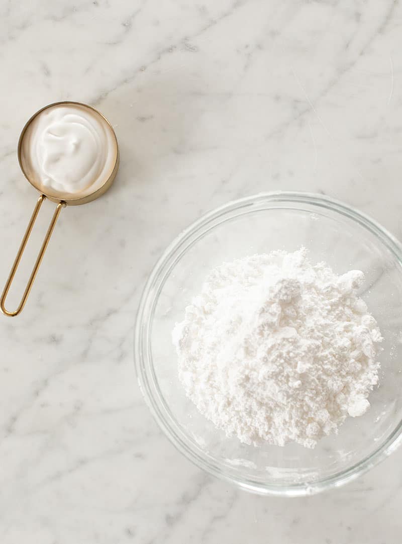 Powdered sugar and coconut milk on a measuring cup.