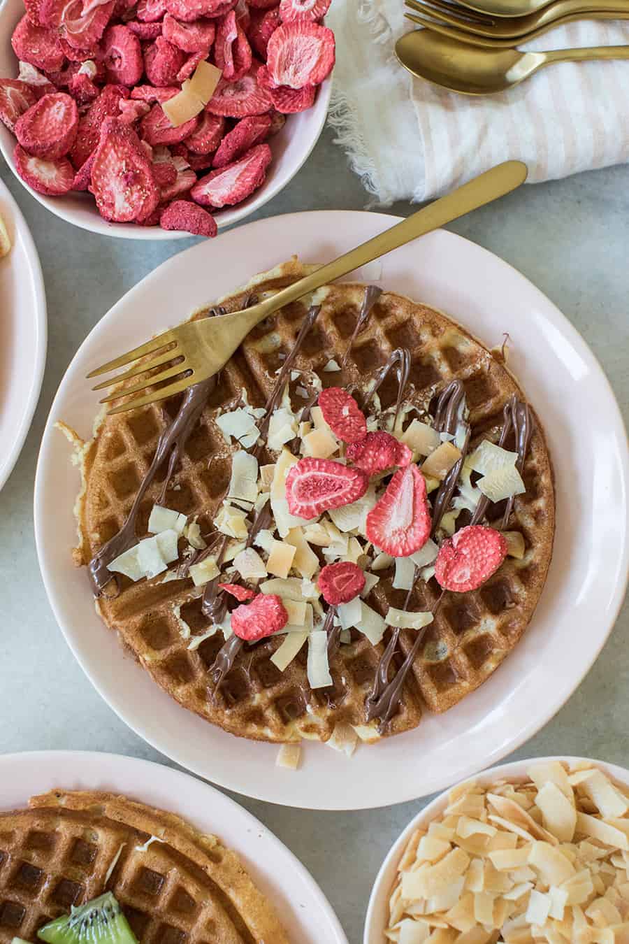 Nutella drizzled over waffles and strawberries.